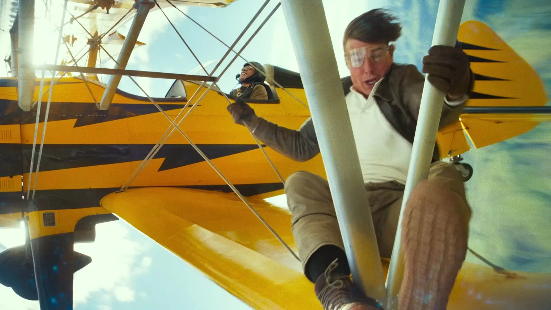 A still of Tom Cruise clinging to an airplane in the middle of the air from the new MIssion Impossible movie