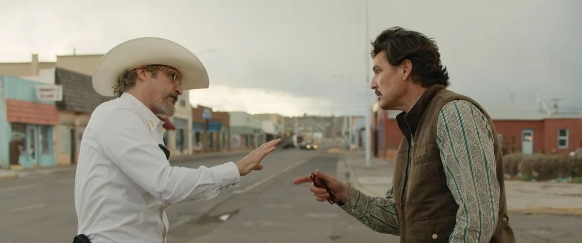 A still from Eddington showing Joaquin Phoenix and Pedro Pascal yelling at each other in the middle of the street