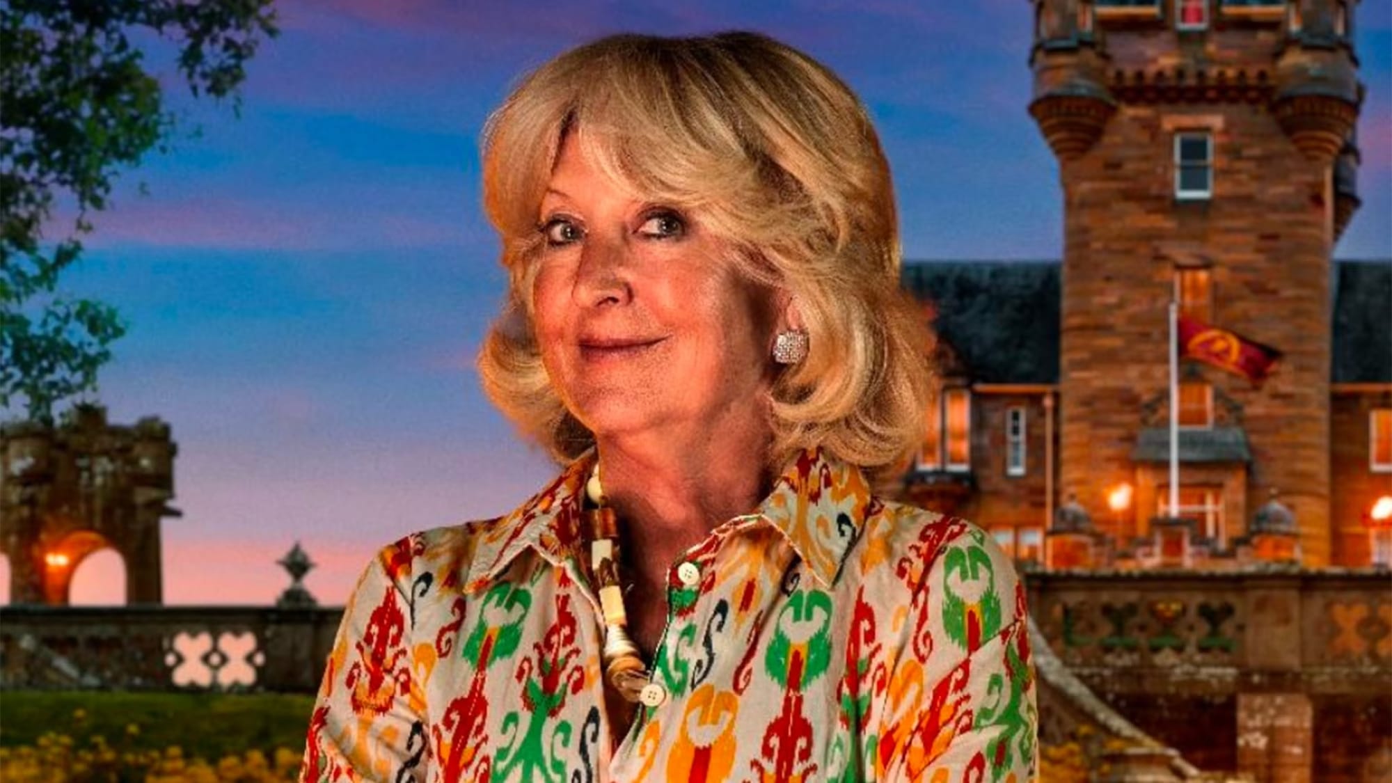 An image of Fiona from The Traitors UK, a smiling, very nice-looking blonde woman in her 60s wearing a brightly patterned shirt and chunky necklace. She looks so innocent, which is why she's terrifying